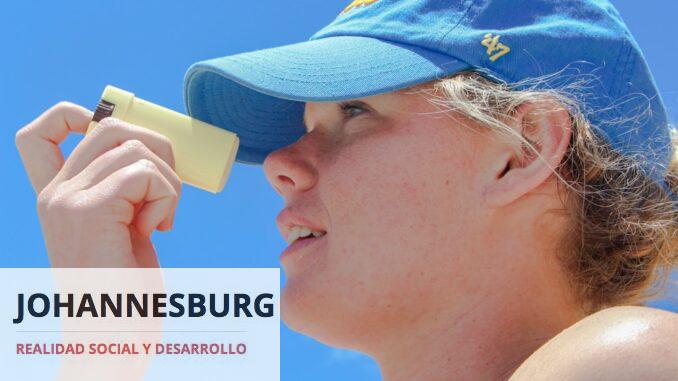 a woman wearing a blue hat looking through a magnifying glass